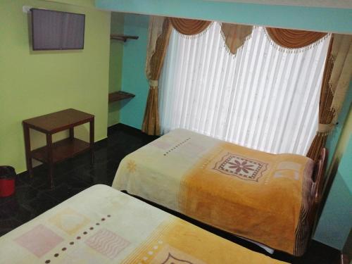 two beds in a room with a window at HOTEL LA 7MA AZUL in Pasto