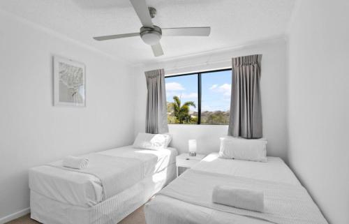 a white room with two beds and a window at Marcoola Beach Resort in Marcoola