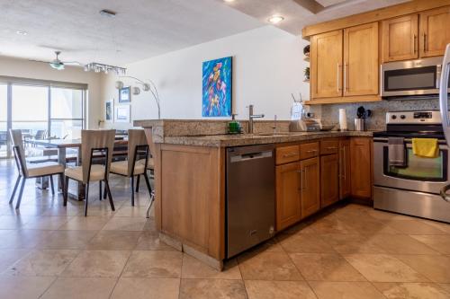 a kitchen with wooden cabinets and a table with chairs at Playa Blanca Condo - 9th Floor Ocean Views! in San Carlos