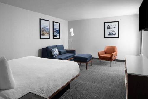 バーバンクにあるCourtyard Los Angeles Burbank Airportのベッドと椅子が備わるホテルルームです。