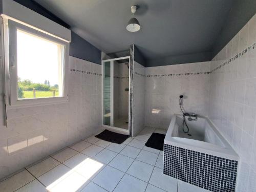 La salle de bains blanche est pourvue d'une baignoire et d'une fenêtre. dans l'établissement Holiday Home near Cap Frehel Emerald Coast, à Plévenon