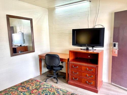 Zimmer mit einem Schreibtisch, einem TV und einem Stuhl in der Unterkunft Border Motel in Calexico