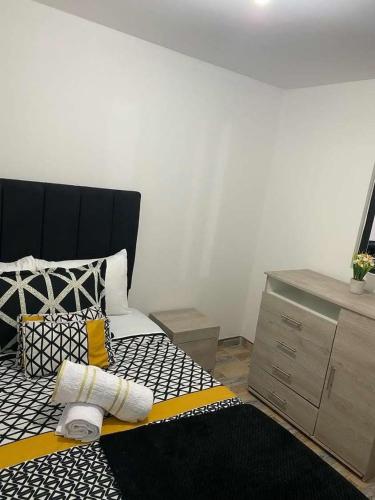 a bedroom with a black and yellow bed and a dresser at Hotel Amatista-Cerca al Aeropuerto in Bogotá
