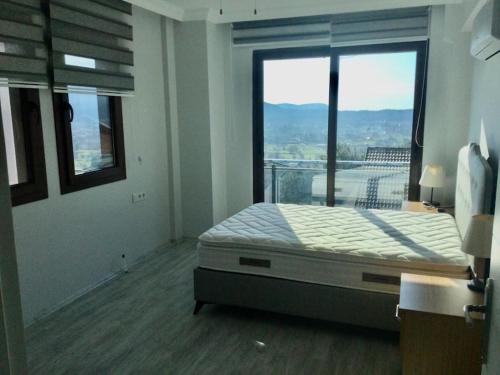 a bedroom with a bed and a large window at Fethiyede Müstakil Villa Havuzlu in Fethiye