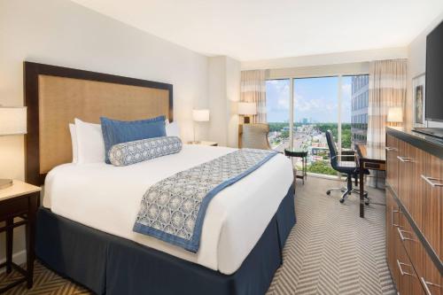a hotel room with a bed and a desk and a window at The Westshore Grand, A Tribute Portfolio Hotel, Tampa in Tampa