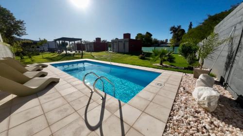 uma piscina com uma cadeira ao lado de uma casa em Aires del Valle em San Agustín de Valle Fértil