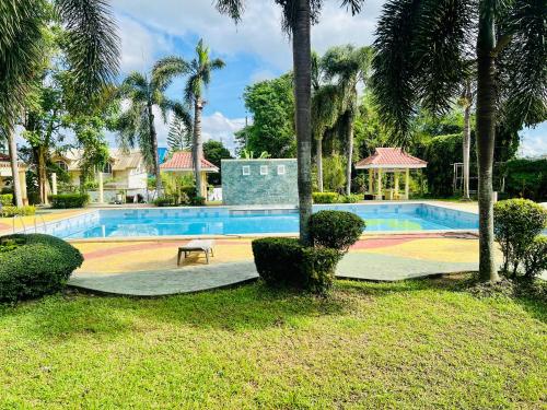 uma piscina com um banco e palmeiras em Awesome 2 bedrooms, living & dining area em General Trias