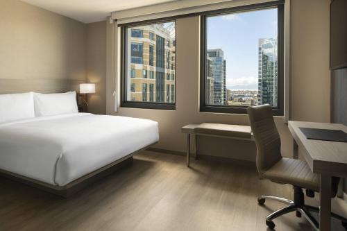 a hotel room with a bed and a desk and windows at AC Hotel by Marriott Oakland Downtown in Oakland