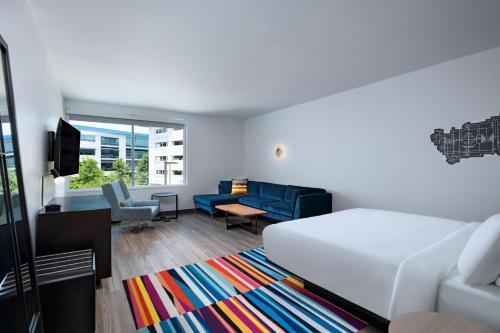 a bedroom with a bed and a living room with a couch at Aloft Austin Southwest in Austin