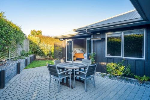 eine Terrasse mit einem Tisch und Stühlen sowie ein Haus in der Unterkunft Peaceful on Punawai in Taupo