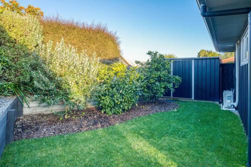 a garden with green grass and a fence at Peaceful on Punawai in Taupo