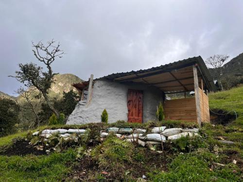 una pequeña casa con una puerta de madera en una colina en casa de los picapiedra en Sesquilé