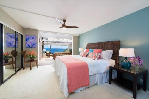 een slaapkamer met een bed en een tafel met een lamp bij Puu Poa Ocean Bluff Condo, Incredible Views, Walk to Beaches, Pool & Tennis in Princeville