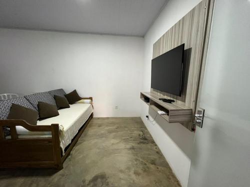 um quarto com uma cama e uma televisão de ecrã plano em Casa Esmeralda em Alto Paraíso de Goiás