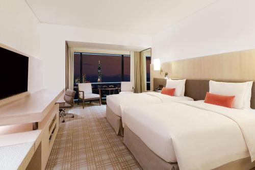 a hotel room with two beds and a television at Taipei Marriott Hotel in Taipei