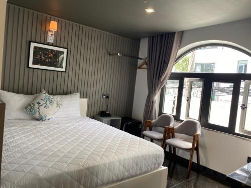 - une chambre avec un lit, deux chaises et une fenêtre dans l'établissement Đông Như 3, à Hô-Chi-Minh-Ville