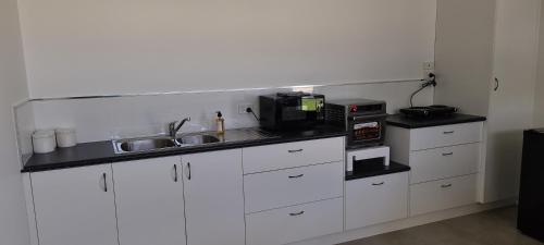 a kitchen with white cabinets and a sink and a microwave at ENGEDI in Tongala