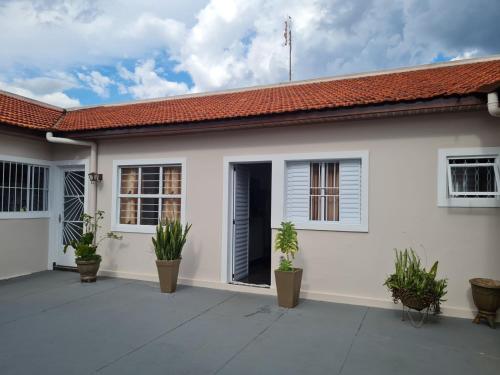 ein weißes Haus mit Pflanzen davor in der Unterkunft Casa com quarto e suíte in São Miguel Arcanjo