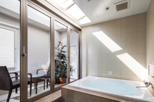 uma casa de banho com uma banheira, uma mesa e cadeiras em Hotel Lei em Funabashi