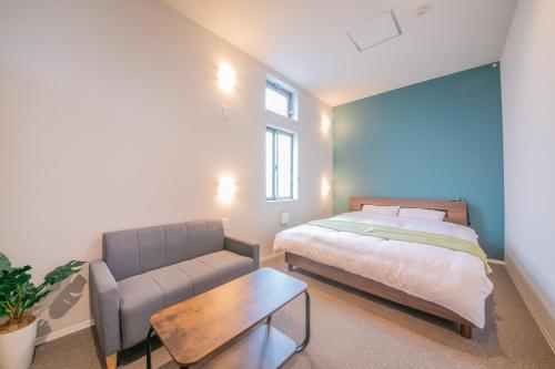 a bedroom with a bed and a couch and a table at KIZUNA HOTEL Gojo Kiyomizu-dera Kamogawa in Kyoto