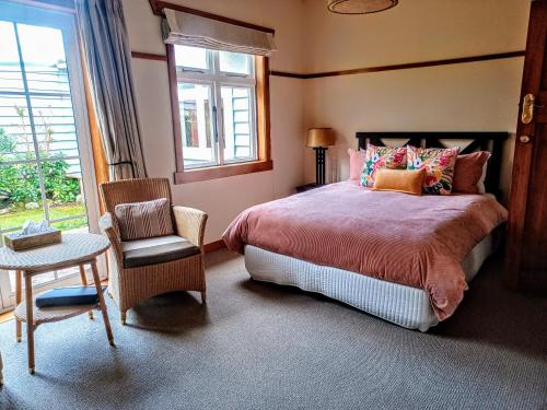a bedroom with a bed and a chair and a window at Lake Brunner Eco Lodge in Moana