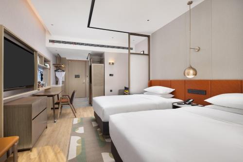 順義にあるHome2 Suites by Hilton Beijing Shunyiのベッド2台、薄型テレビが備わるホテルルームです。