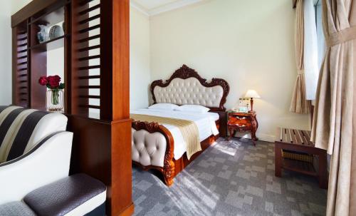 Victory Sai Gon Hotel في مدينة هوشي منه: غرفة نوم بسرير وكرسي وطاولة