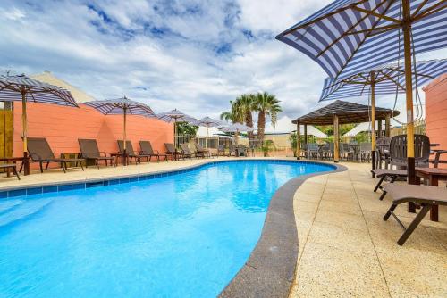 a large swimming pool with chairs and umbrellas at Osprey Holiday Village Unit 108 in Exmouth