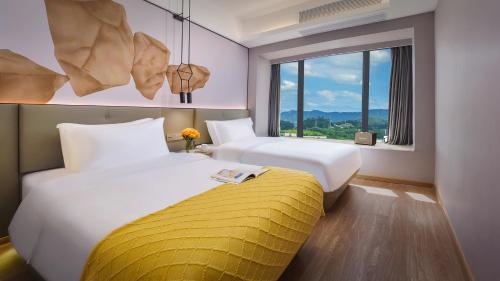 a hotel room with two beds and a window at Lanz International Hotel Shenzhen Guangming Wisdom City in Tiantangwei