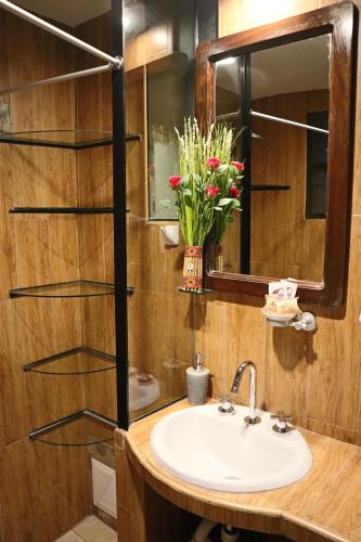 a bathroom with a sink and a mirror and flowers at Cusco Bed and Breakfast in Cusco