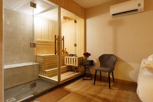 Victory Sai Gon Hotel في مدينة هوشي منه: دش زجاجي في غرفة النوم مع كرسي وطاولة