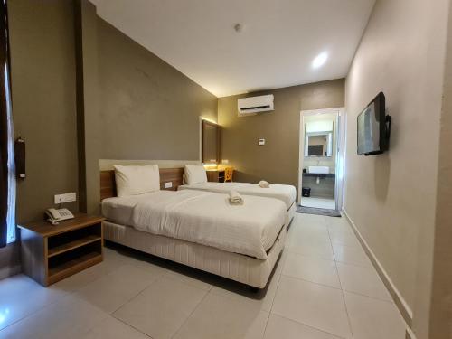 a bedroom with a large bed and a television at Ants Hotel in Kangar