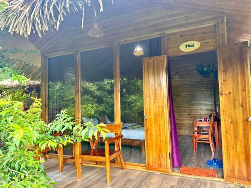 a porch of a wooden house with a table and chairs at Bac Ha Lodge Retreat in Bắc Hà