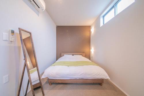 a small bedroom with a bed and a window at KIZUNA HOTEL Gojo Kiyomizu-dera Kamogawa in Kyoto