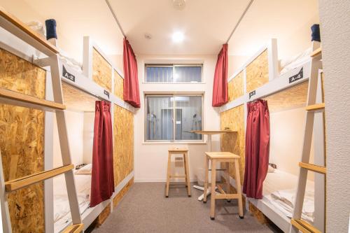 a dorm room with bunk beds and a stool at KIZUNA HOTEL Gojo Kiyomizu-dera Kamogawa in Kyoto