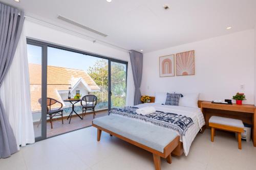 a bedroom with a bed and a desk and a balcony at Cosa villages in Vung Tau
