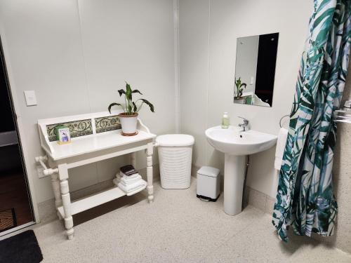 Baño blanco con lavabo y aseo en Glenwood Akaroa Bush Retreat - Kanuka Hut, en Akaroa