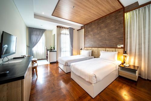 una camera d'albergo con due letti e una televisione di LCS Hotel & Apartment a Phnom Penh