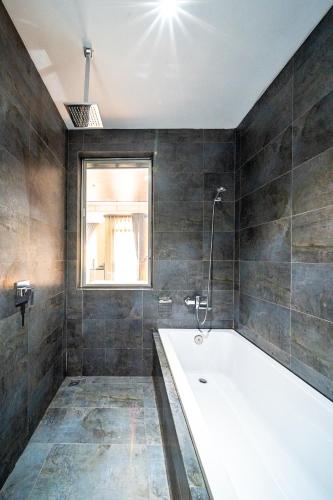 a bathroom with a bath tub and a window at LCS Hotel & Apartment in Phnom Penh