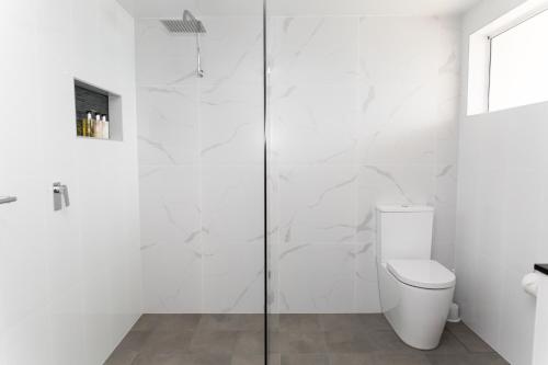 a white bathroom with a shower and a toilet at Amooran Oceanside Apartments and Motel in Narooma