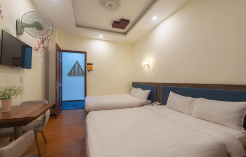 a bedroom with two beds and a table and a desk at Tasme Hotel in Da Lat