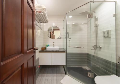 a bathroom with a glass shower and a sink at Tasme Hotel in Da Lat