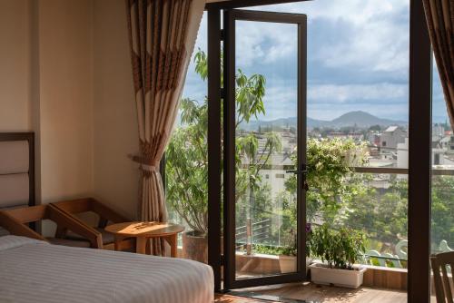 a hotel room with a bed and a large window at Tasme Hotel in Da Lat