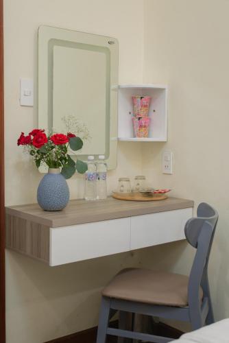 a counter with a mirror and a vase with red roses at Tasme Hotel in Da Lat