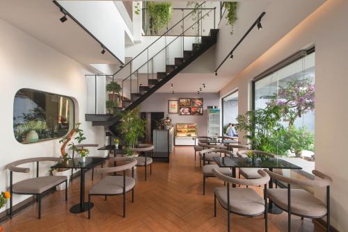 a restaurant with tables and chairs and a staircase at Tasme Hotel in Da Lat