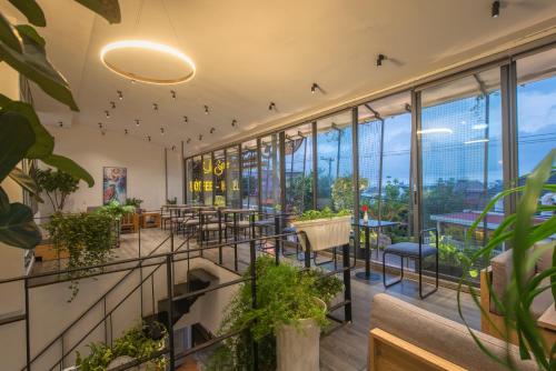 a restaurant with plants and tables and windows at Tasme Hotel in Da Lat