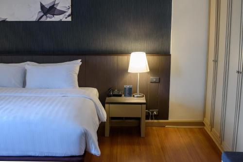 a bedroom with a bed and a table with a lamp at SC Park Hotel in Bangkok