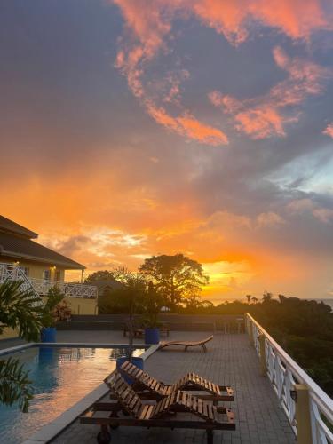 a sunset from the deck of a resort with benches at The Victory Villa in Parrot Hall