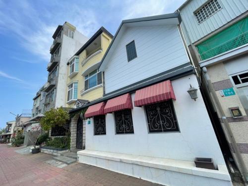 台南市にある臺南安平 -安平安逸民宿 Anping Guest Houseの通り赤い日よけの白い建物
