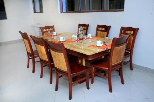 a dining room table with chairs and a wooden table at DISCOVERY COURTS HOTEL in Entebbe